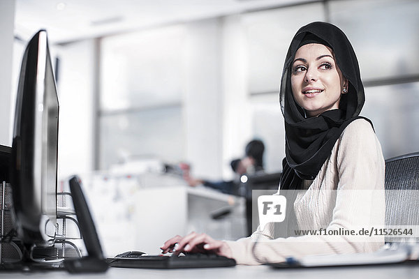 Junge Frau mit Hijab auf dem Schreibtisch im Büro