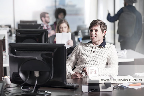 Lächelnder Mann am Schreibtisch im Büro
