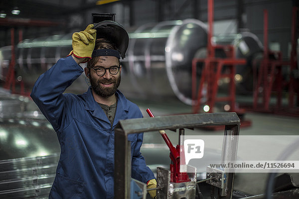 Porträt eines lächelnden Mannes mit einer Schweißmaske in einer Fabrik
