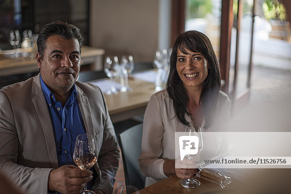 Porträt von lächelndem Mann und Frau mit Weingläsern