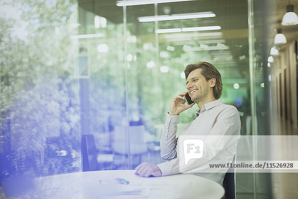 Smiling businessman talking on cell phone in conference room