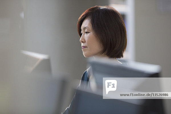 Fokussierte Geschäftsfrau bei der Arbeit am Computer im Büro