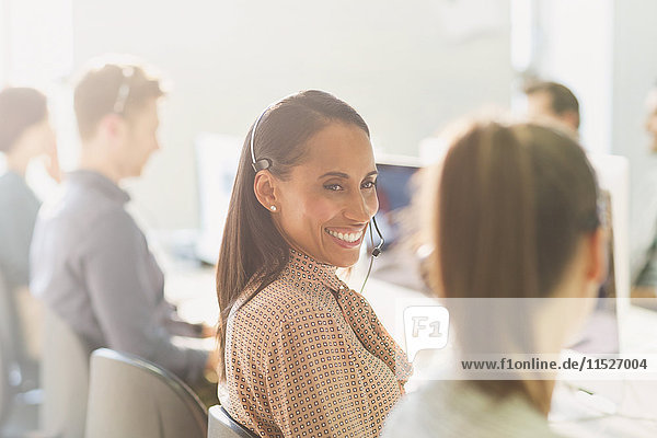 Smiling female telemarketers wearing headsets talking in sunny office