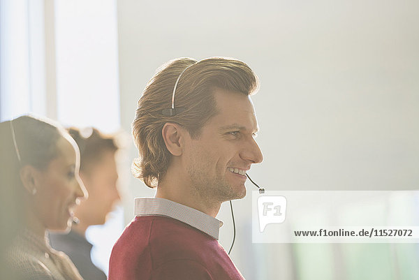 Smiling male telemarketer wearing headset talking on telephone