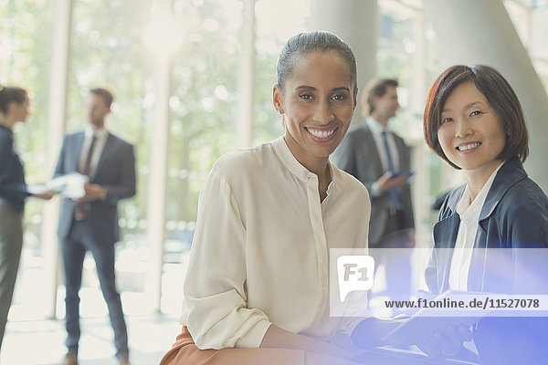 Portrait lächelnde Geschäftsfrauen mit digitalem Tablett in der Bürolobby