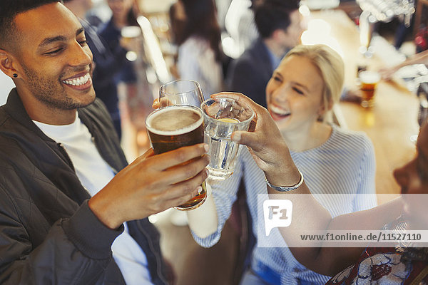 Enthusiastische Freunde toasten Bier und Weingläser an der Bar
