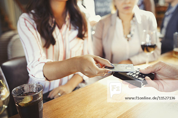 Barkeeperin mit Kreditkarte kontaktlos bezahlen an der Bar