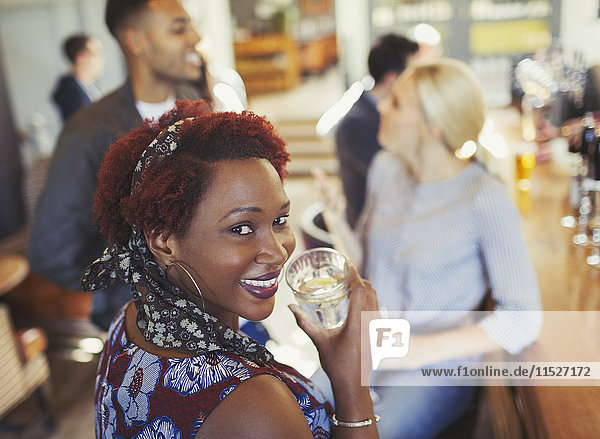 Portrait lächelnde Frau trinkt Wasser und redet mit Freunden an der Bar