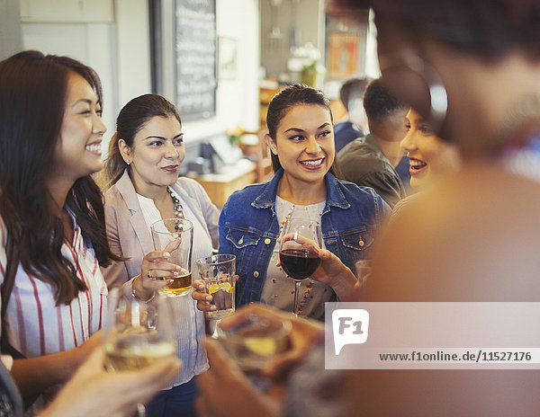 Women friends talking and drinking beer and wine at bar