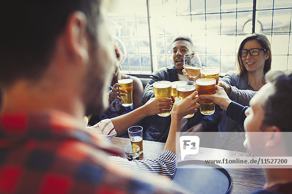 Friends celebrating  toasting beer glass at bar table