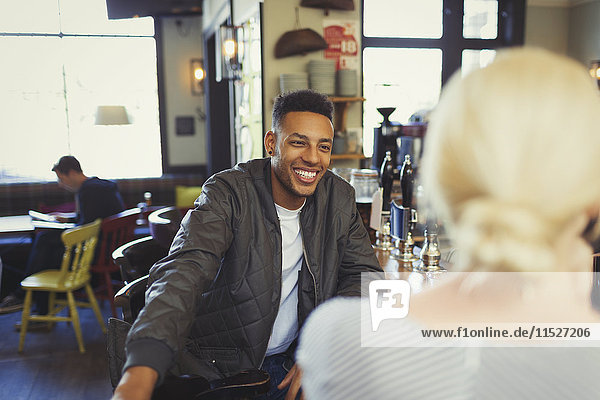 Smiling man talking to woman in bar