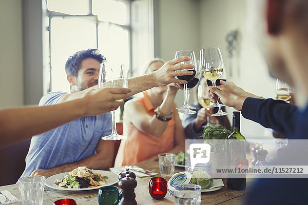 Friends celebrating  toasting wine glasses and dining at restaurant table