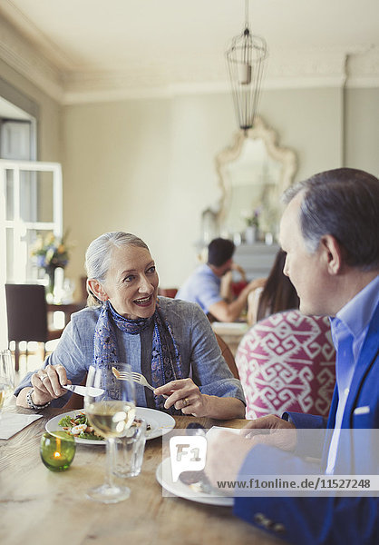 Seniorenpaar beim Reden und Essen am Restauranttisch