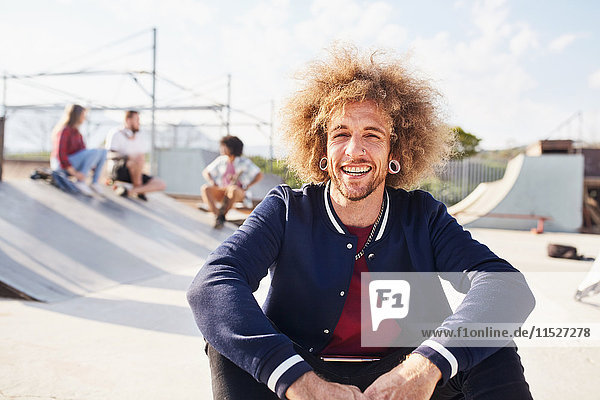 Portrait selbstbewusster junger Mann mit Afro im sonnigen Skatepark