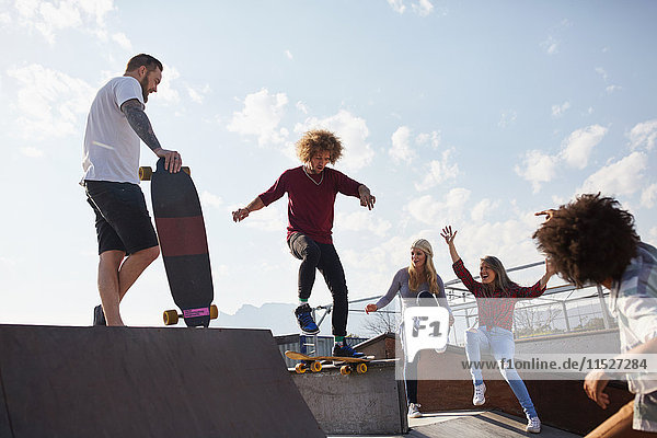 Friends skateboarding at sunny skate park