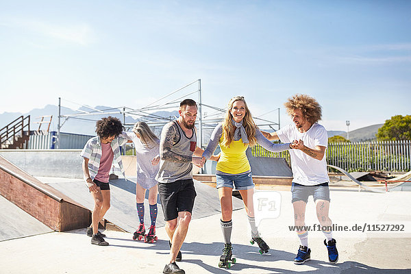 Freunde Rollschuhlaufen im sonnigen Skatepark