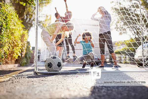 Freunde spielen Fußball auf der sonnigen städtischen Sommerstraße.