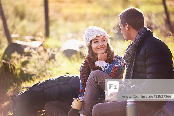 Young couple with backpacks camping  drinking coffee