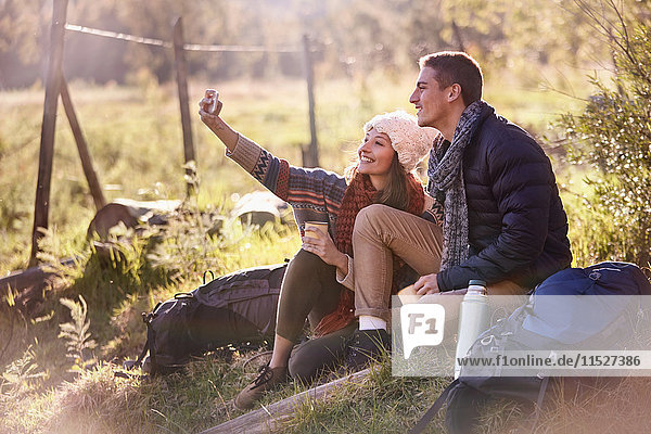 Young couple taking a break from hiking  taking selfie with camera phone