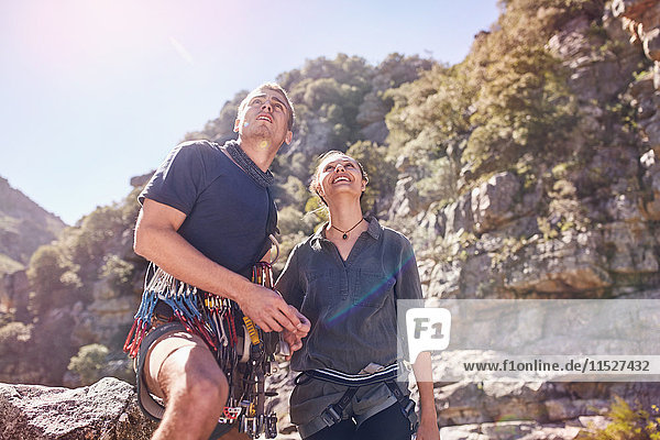 Young man and woman rock climbing  looking up at sunny cliffs