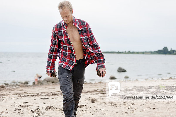 Mann mit aufgeknöpftem Hemd läuft am Strand
