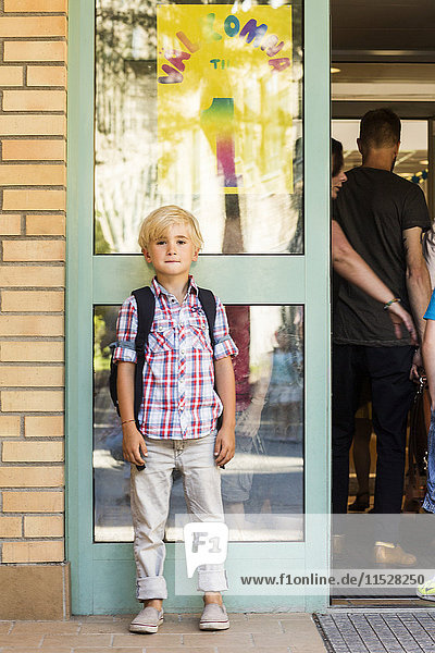 Junge vor dem Schulgebäude stehend