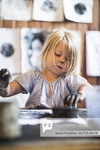 Small girl painting with black paint