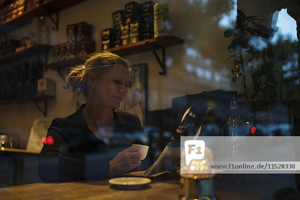 Frau liest Zeitung in einem Cafe