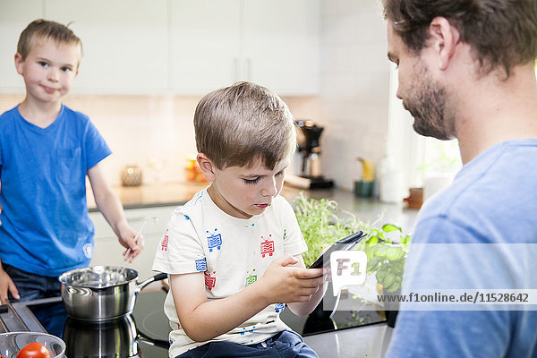 Junge spielt mit Smartphone in der Küche