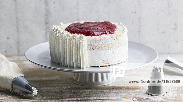 Cake with whipped cream and fruit sauce on cake stand