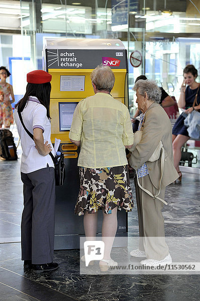 Frankreich  Westfrankreich  Bahnhof von Nantes  Mitarbeiter der SNCF  der älteren Menschen hilft  ihre Fahrkarten am Fahrkartenautomaten in der Abflughalle zu kaufen.
