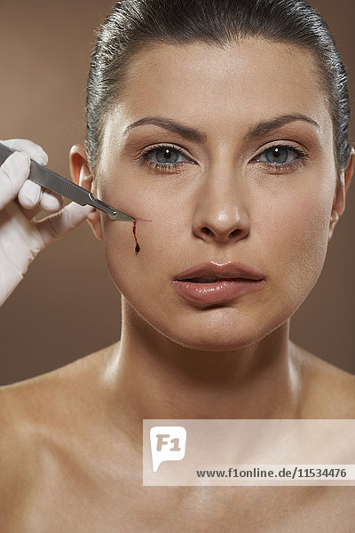 Frau mit Gesichtsschnitt mit Skalpell