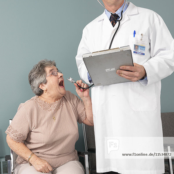 Frau schreit ins Stethoskop des Arztes