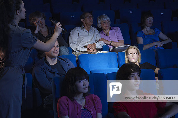 Platzanweiser leuchtet mit einer Taschenlampe auf einen leeren Sitz im Kino