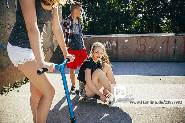 Drei Jugendfreunde mit Roller und Skateboard