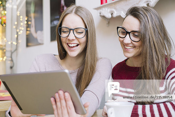 Zwei junge Frauen haben Spaß mit dem digitalen Tablett in einem Cafe