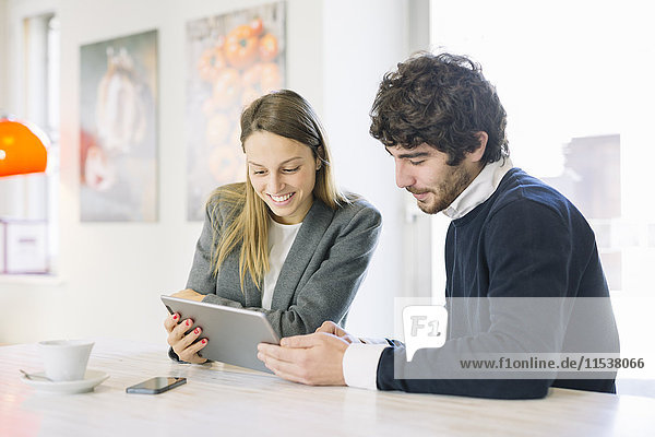 Zwei Kollegen in einem Café beim Betrachten des digitalen Tabletts