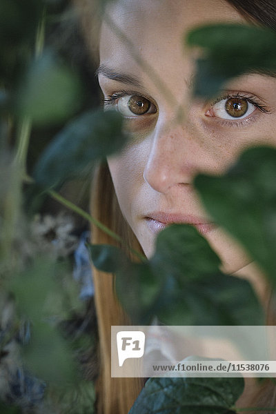 Porträt einer attraktiven jungen Frau hinter Blättern