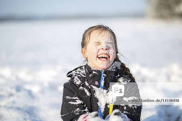Portrait of laughing girl with snow-covered face