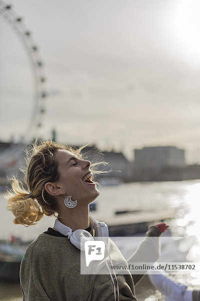 UK  London  laughing woman with headphones at River Thames