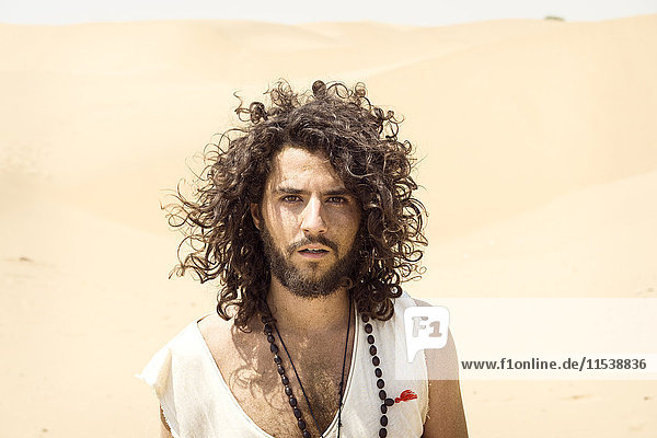 Porträt eines Mannes mit Bart und lockigem Haar in der Wüste