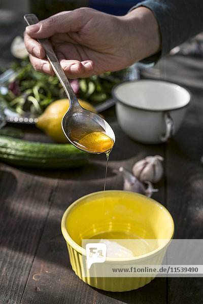 Frühlingssalat  Dressing mit Honig  Joghurt und Zitrone  Hand mit Löffel und Honig