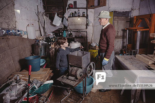 Älterer Mann erklärt seinem Enkel etwas in seiner Werkstatt.