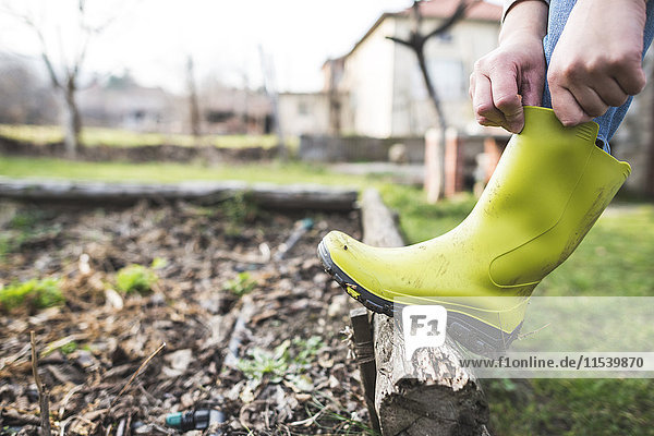 Frau zieht ihre Wellington-Stiefel im Garten an  Nahaufnahme