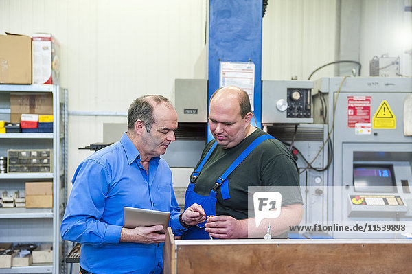 Zwei Männer in der Fabrik  die in einer Fabrik reden.