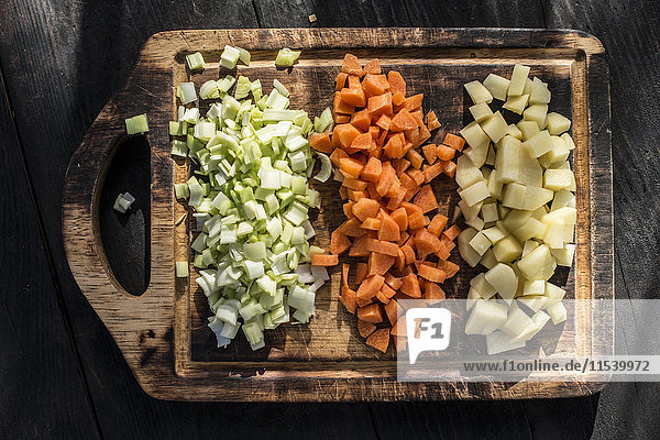 Karotten-  Kartoffel- und Zwiebelwürfelreihen auf Holzbrettchen