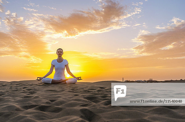 Frau praktiziert Yoga auf Sanddünen