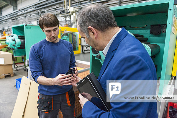 Manager and worker in plastics factory discussing production quality
