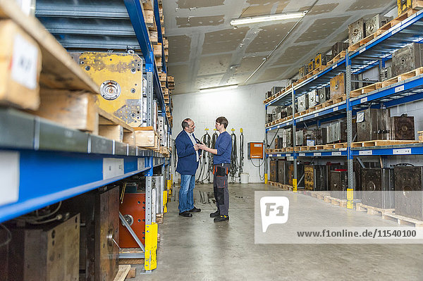 Two men examining machine blocks in storehouse