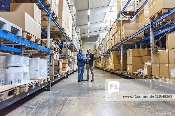 Two managers discussing packaging and shipment in storage hall